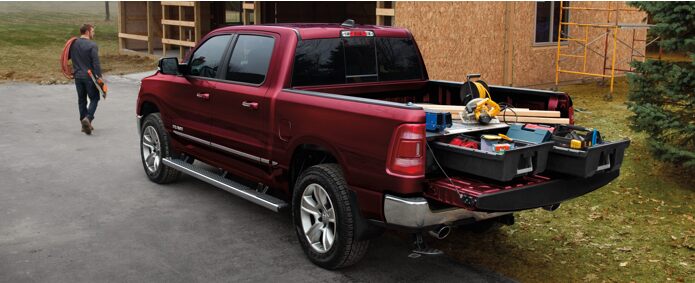 A 2021 Ram 1500 with its truck bed loaded with lumber and tools.